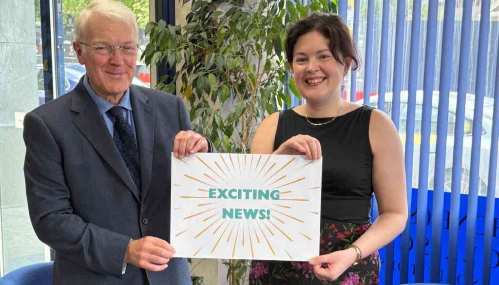 Directors of Woolliscrofts Solicitors holding 'exciting news' sign.